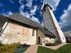 The Sava Bohinjka River rushes under a stone bridge with an expansive view of Bohinj Lake from underneath. The medieval St. John the Baptist Church and its onion-domed Bell Tower in Lake Bohinj, Slovenia.